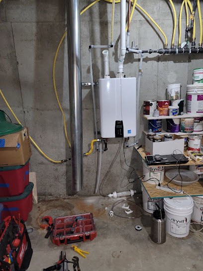 White tankless water unit mounted on a concrete wall with tools, buckets, and paint cans nearby